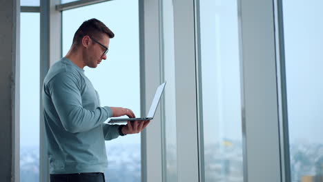hombre trabajando en una computadora portátil por la ventana