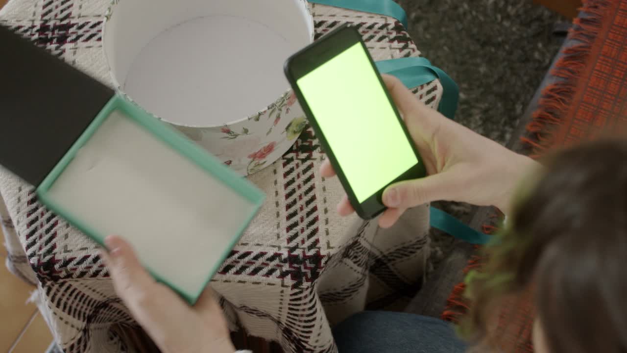 manos de la mujer que abre una caja de regalos y encuentra un teléfono celular con pantalla verde