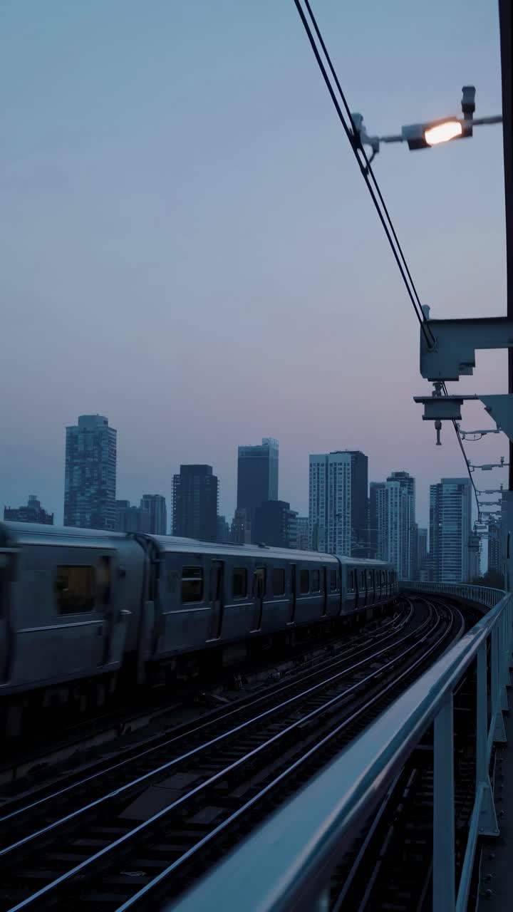 A cityscape video at dusk captures a train from a low angle, highlighting urban architecture
