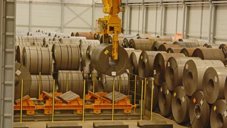 wide view of a large crane putting down a heavy steel coil in a automated factory