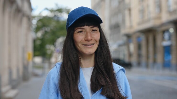 Ritratto di una donna con l'apparecchio ortodontico e un cappellino da baseball in una strada di città