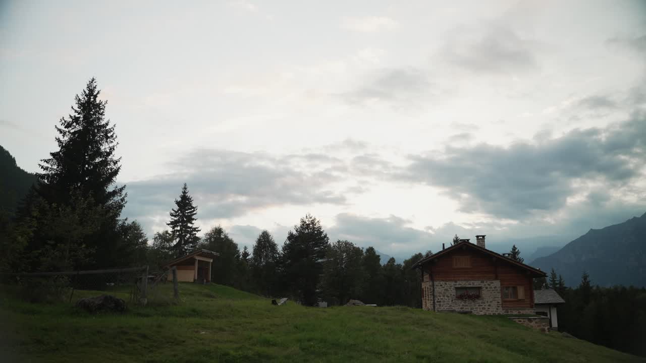 atardecer tardío detrás de una casa de montaña y los árboles en los alpes italianos