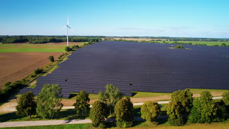 solar energy production farm on sunny day with blue sky above, aerial orbit left