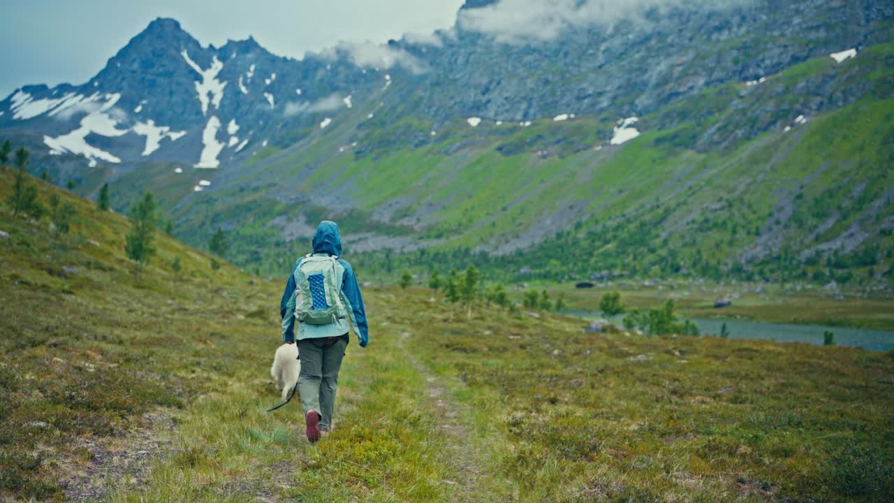 SørTverrfjord, Loppa, Finnmark, Norja – Vaeltaja kävelee koiransa kanssa hiljaista polkua pitkin karujen vuorten läpi – Käsivaralta kuvattu.