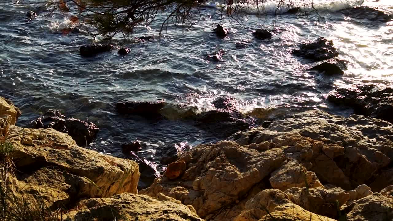 Onde che si infrangono sulla riva della spiaggia durante l'ora d'oro, Murter, Croazia