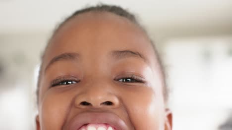 portrait close up of happy african american girl looking at camera and smiling, in slow motion