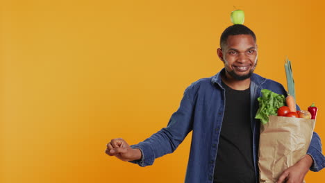 un tipo vegano lúdico bailando con una manzana colocada en su cabeza