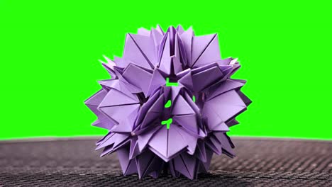 violet origami flower on green screen.