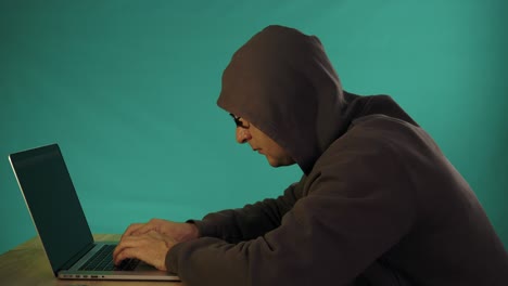 hacker typing code. green type on screen. night and low key. close-up. indoors night work. programmer coding software of site. a hacker is preparing an attack on hacking portal.
