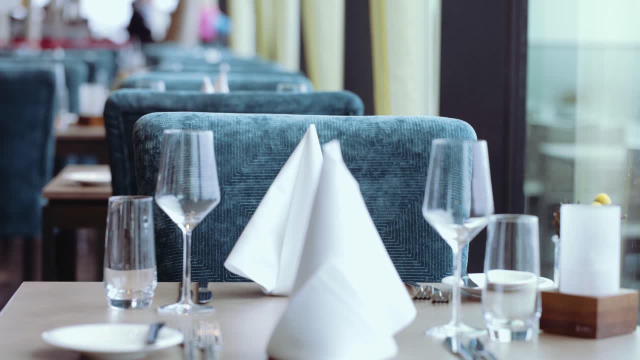 Server sets chair of a table in restaurant. Preparing dinner table at a restaurant
