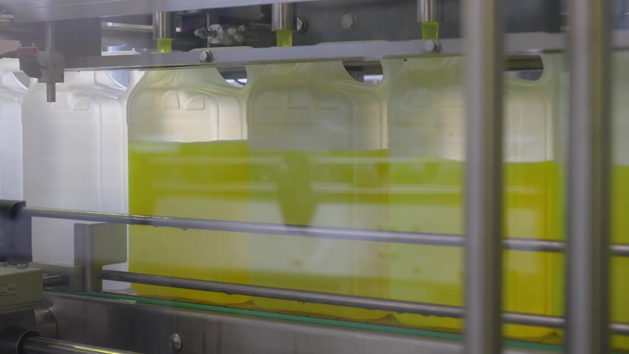 Close Up of Automated Factory Conveyor Machine Fill Plastic Bottles with Yellow Antifreeze Coolant Liquid
