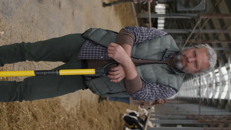 vertical portrait of middle-aged man with shovel at farm