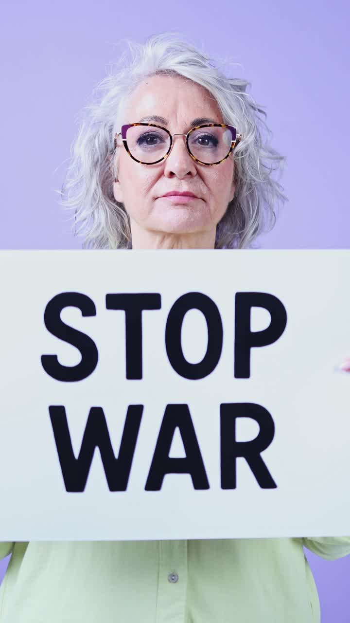 Donna anziana seria che tiene un cartello con scritto 'Stop alla guerra'