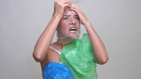 a terrified woman wrapped in plastic trash