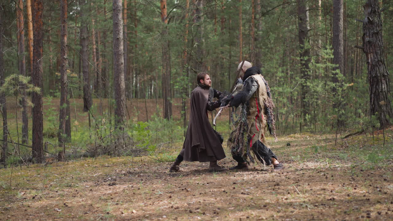 el joven caballero y el enojado ogro luchan en el claro del bosque de abetos.