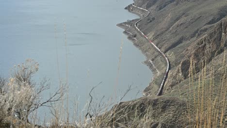 Capturar-El-Sereno-Lago-Kamloops-Con-Una-Vista-Panorámica-De-Un-Tren-De-Carga-A-Lo-Largo-De-La-Costa-Desde-Battle-Bluff