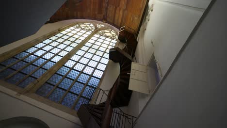 Rotating-Tilt-up-before-a-glass-window-inside-Amsterdam's-Oude-Kerk,-capturing-historic-allure-and-luminous-ambiance