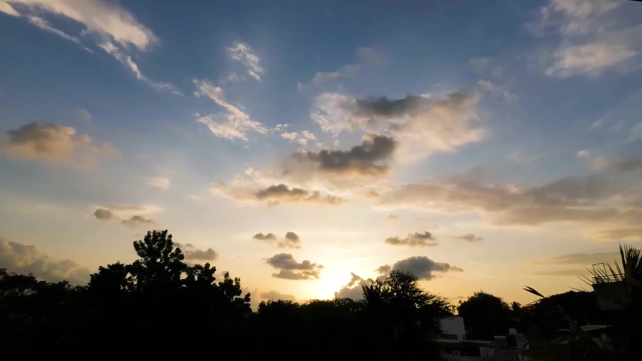 Timelapse gran angular de nubes dramáticas al atardecer moviéndose por el cielo con vibrantes colores vespertinos. Perfecto para fondos cinematográficos, introducciones y visuales de naturaleza