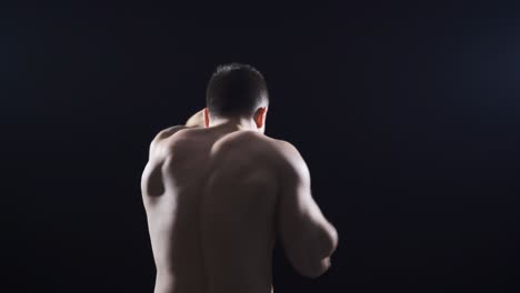 a young man with his back turned shadow boxing at a fast and gentle pace.