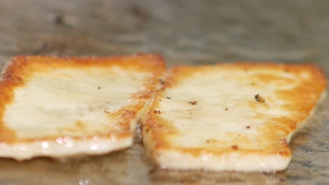 primer plano de queso halloumi chisporroteando en una parrilla y volteado con una espátula después de ser marrón