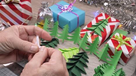 male hands unfold snowflakes made of paper on a table with christmas crafts and gifts.