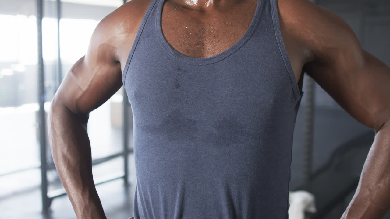 Sweating and standing, man in gym wearing tank top after workout
