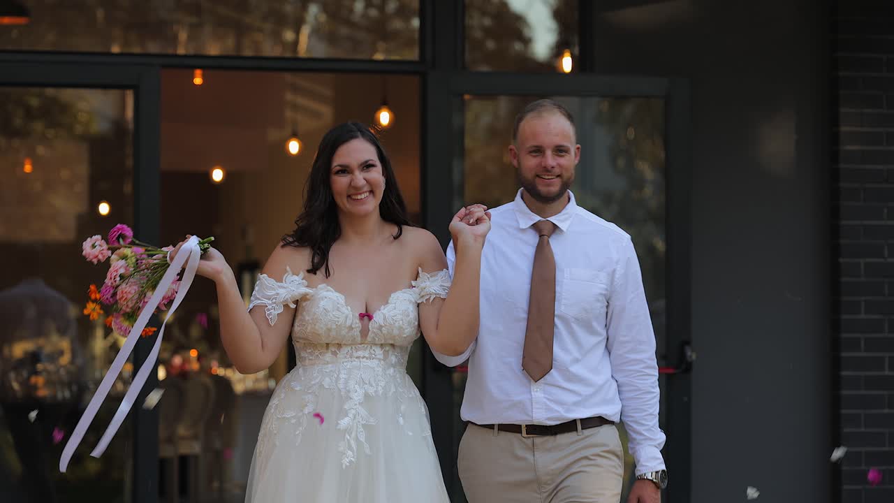 Coppia felice di novelli sposi emerge dal luogo del matrimonio per festeggiare.