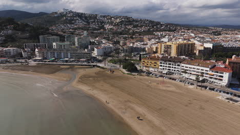 flyover of peniscola beachfront under soft sky with waves gently hitting the shore