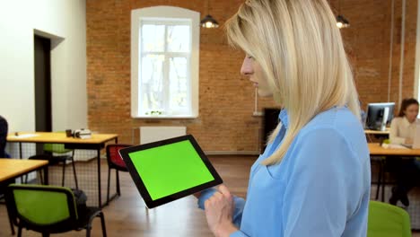 close up of young atractive woman using black tablet with green screen at modern office. camera stabilizer shot. chroma key.