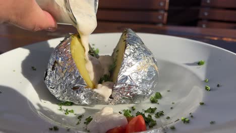 adding fresh sauce with herbs to a baked potato