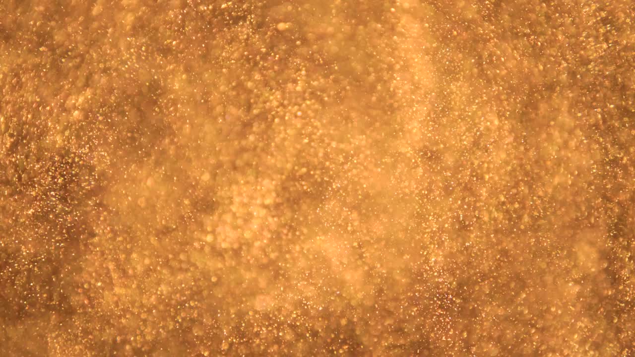 elegantes, detalladas y doradas partículas fluyen con poca profundidad de campo bajo el agua