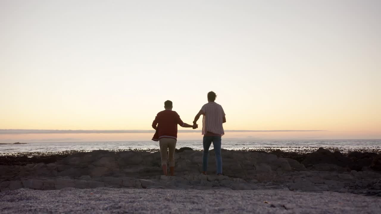 다양한 행복한 동성애 남성 커플이 해가 지는 해변에서 손을 잡고 달리고, 슬로우 모션
