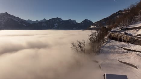 house and winding mountain road on a white hillside overlooking thick fog covering walensee in switzerland