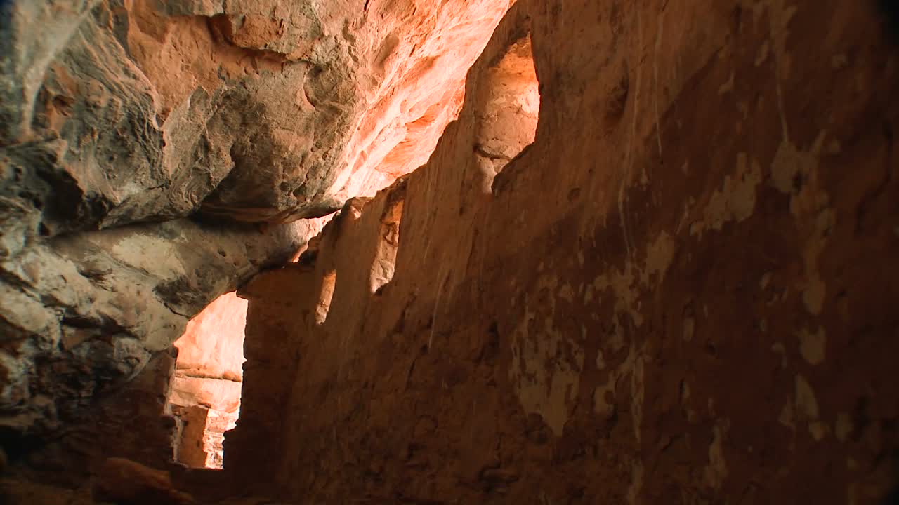 una mujer camina a través de una antigua vivienda en un acantilado indio nativo americano