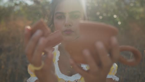 closeup shot of a stunning young woman holding a broken pot staring intently as she brings the pieces back together