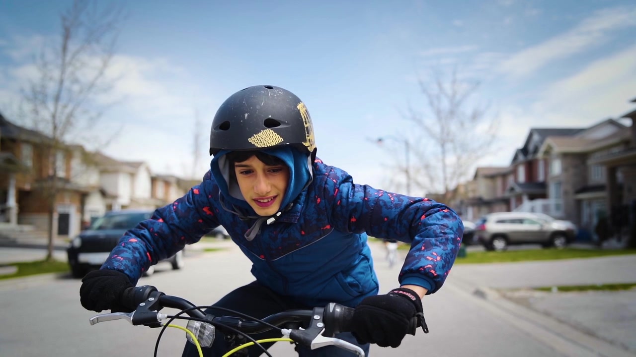 Un ragazzo giovane e felice si diverte a andare in bicicletta per strada.