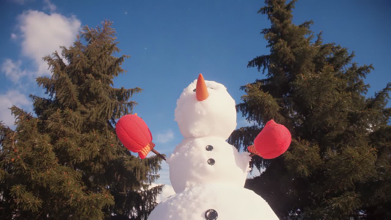 Starting snowflakes drifting around three-tiered snowman in backyard, red mittens and pine trees