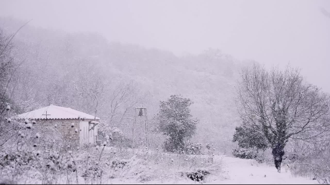 숲 속 의 눈 폭풍 에서 멀리 걸어가는 개 와 함께 있는 사람, 배경 에 있는 교회