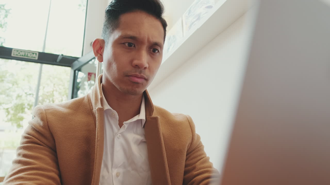 カフェでラップトップに取り組んでいる男
