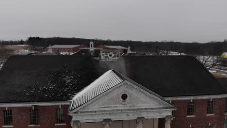 A-winter-drone-shot-flying-over-a-building-and-revealing-the-abandoned-Fairfield-Hills-Hospital-asylum-in-Newtown,-Connecticut