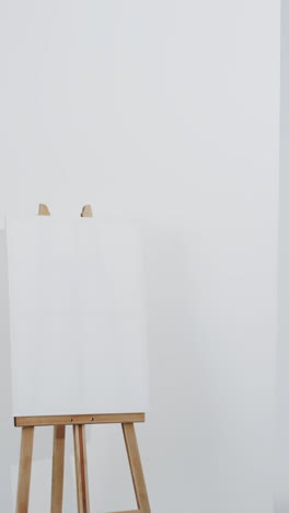vertical video of white canvas sign on wooden easel with copy space on white background