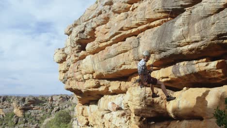 mountaineer rappelling down the hill with the help of rope 4k