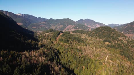 Wide-Shot-of-power-lines-running-through-mountains-on-a-sunny-day-in-the-Fraser-Valley-in-the-Lower-Mainland-in-British-Columbia,-Canada