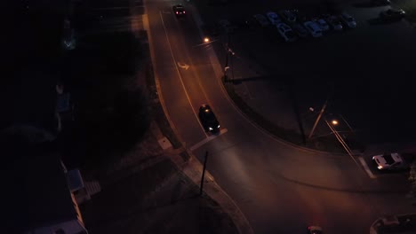 car with headlights stopping at stop line of american town at night. aerial top down shot. vehicles on junction with lighting lantern. traffic scene.