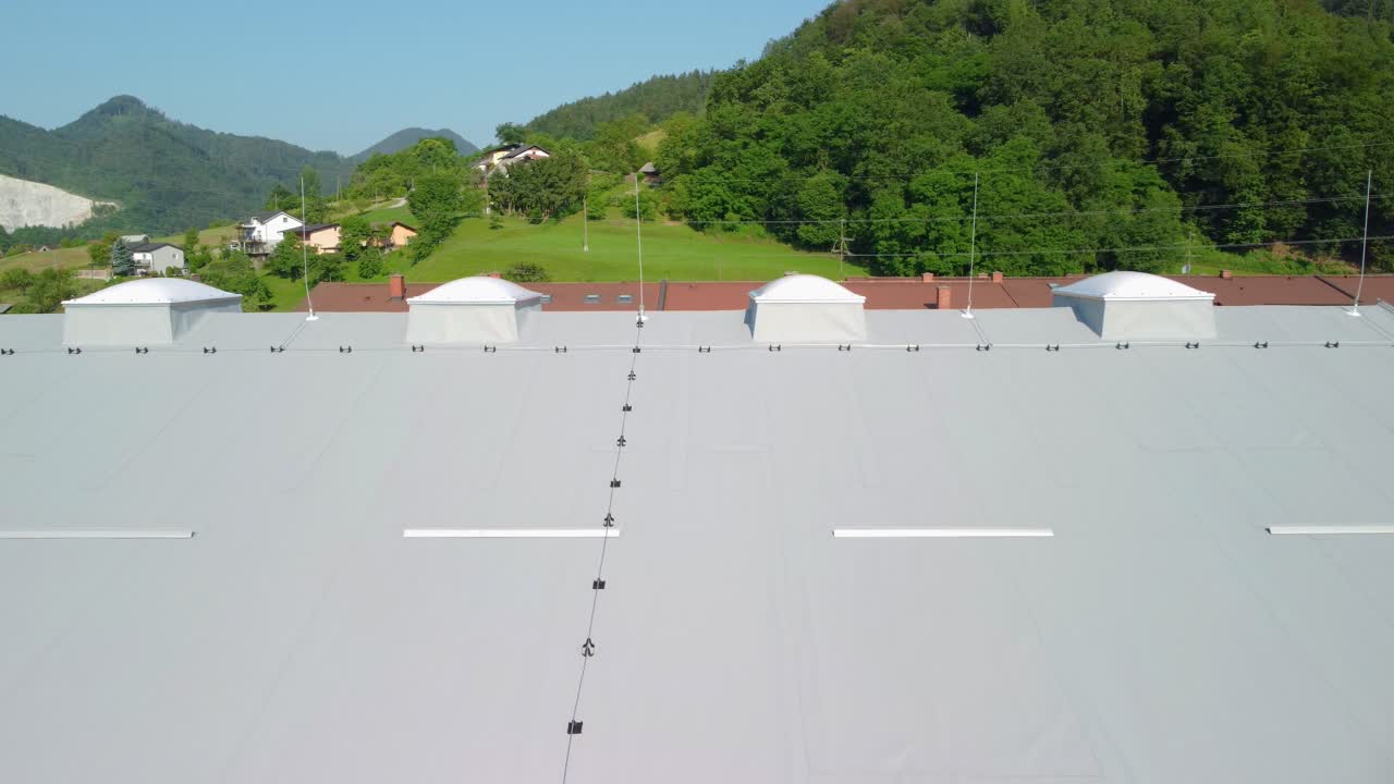 灰色の熱隔離板と防雷線で覆われた屋根に向かって飛ぶ