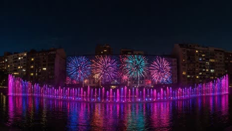 a spectacular display of colorful fireworks and illuminated fountains reflecting over a tranquil body of water at night, creating a mesmerizing urban scene