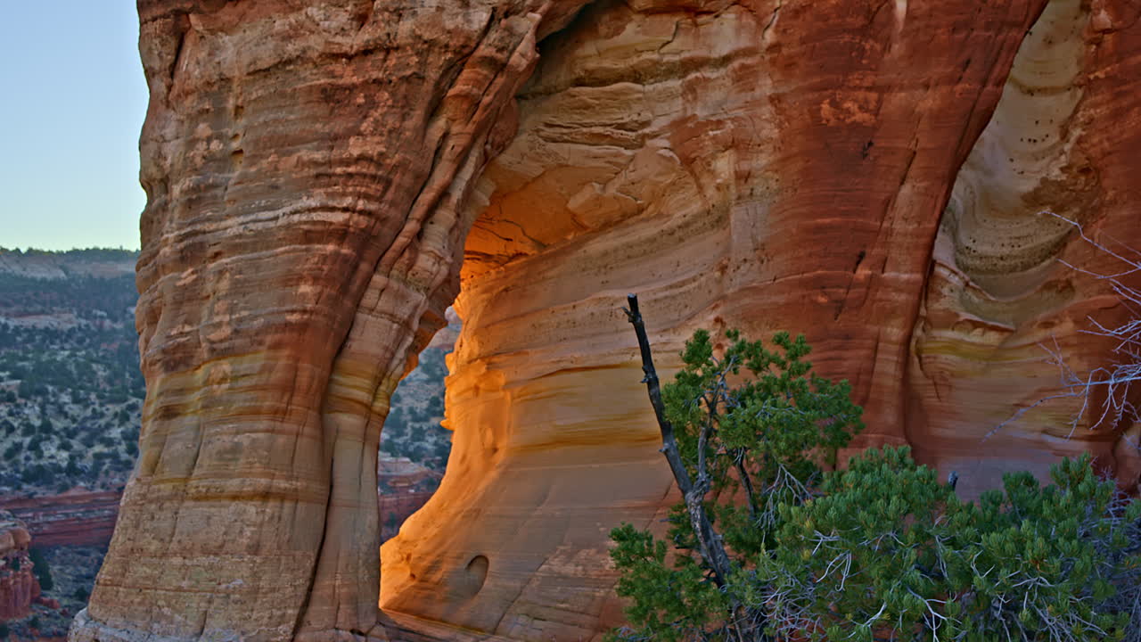 Drone captures an epic sunrise over a natural rock arch in the red desert near Kanab, Utah.