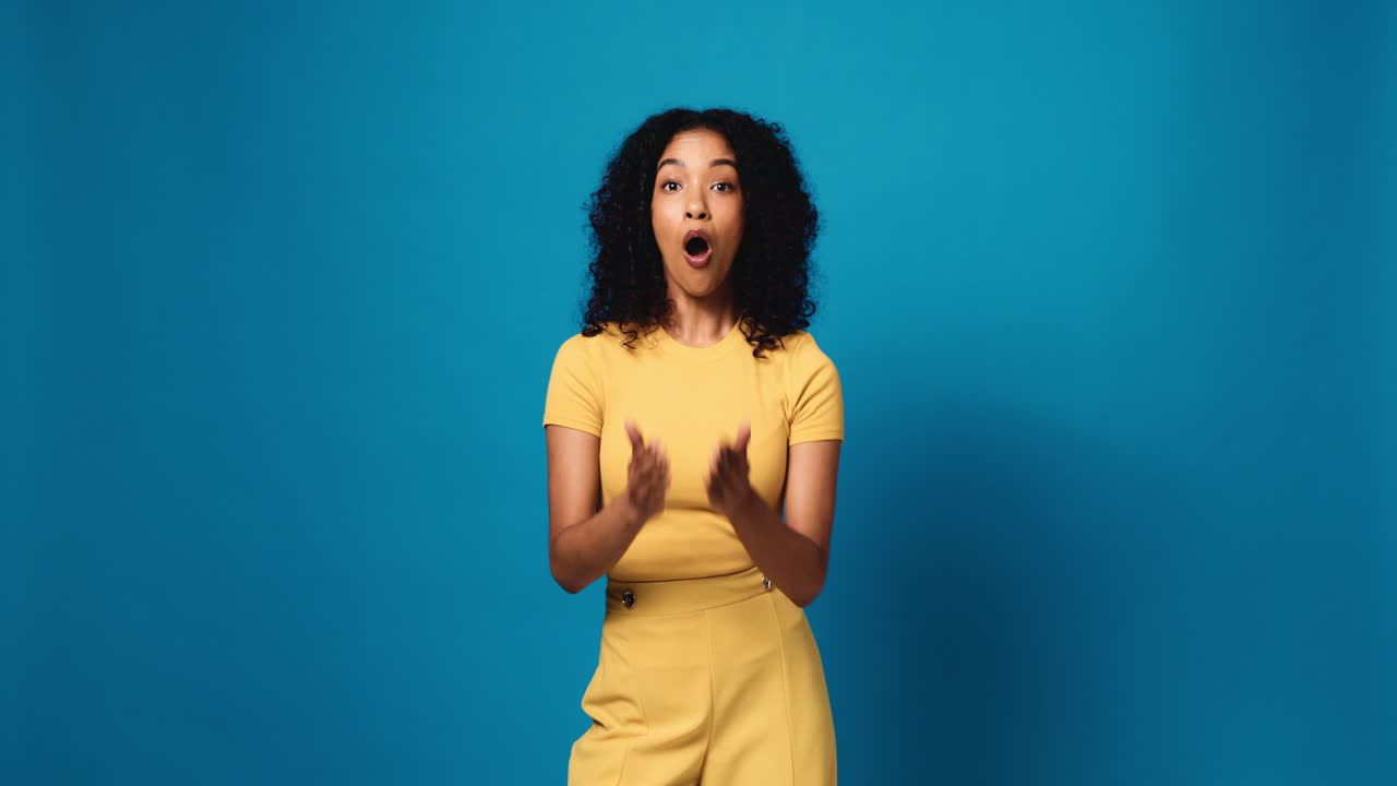 Surprised woman with curly hair on blue background