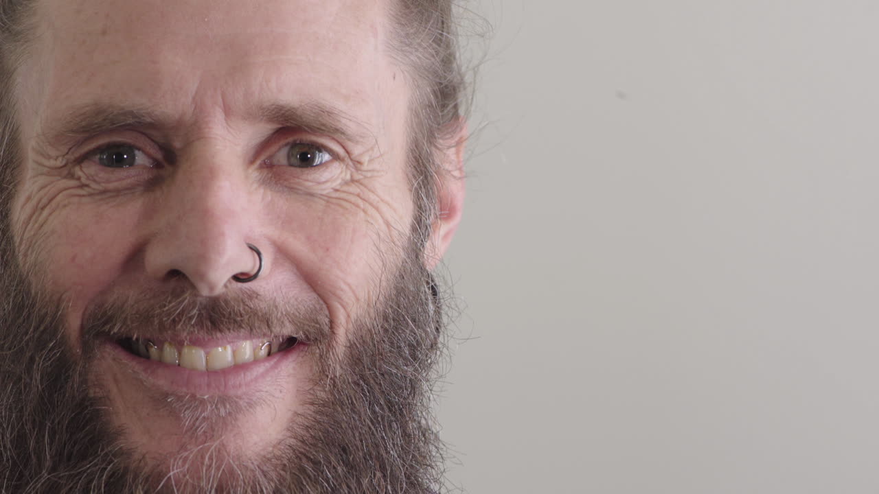 feliz hombre hippie de mediana edad sonriendo alegre maduro barbudo hombre caucásico con anillo en la nariz aislado en un fondo en blanco copia espacio de cerca