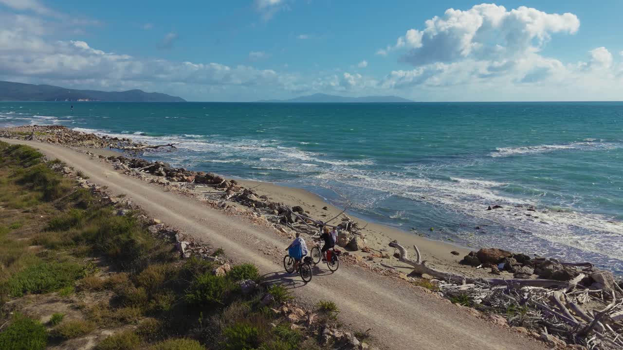 Casal andando de bicicletas elétricas, em passeio ativo e esportivo na Itália, à beira-mar